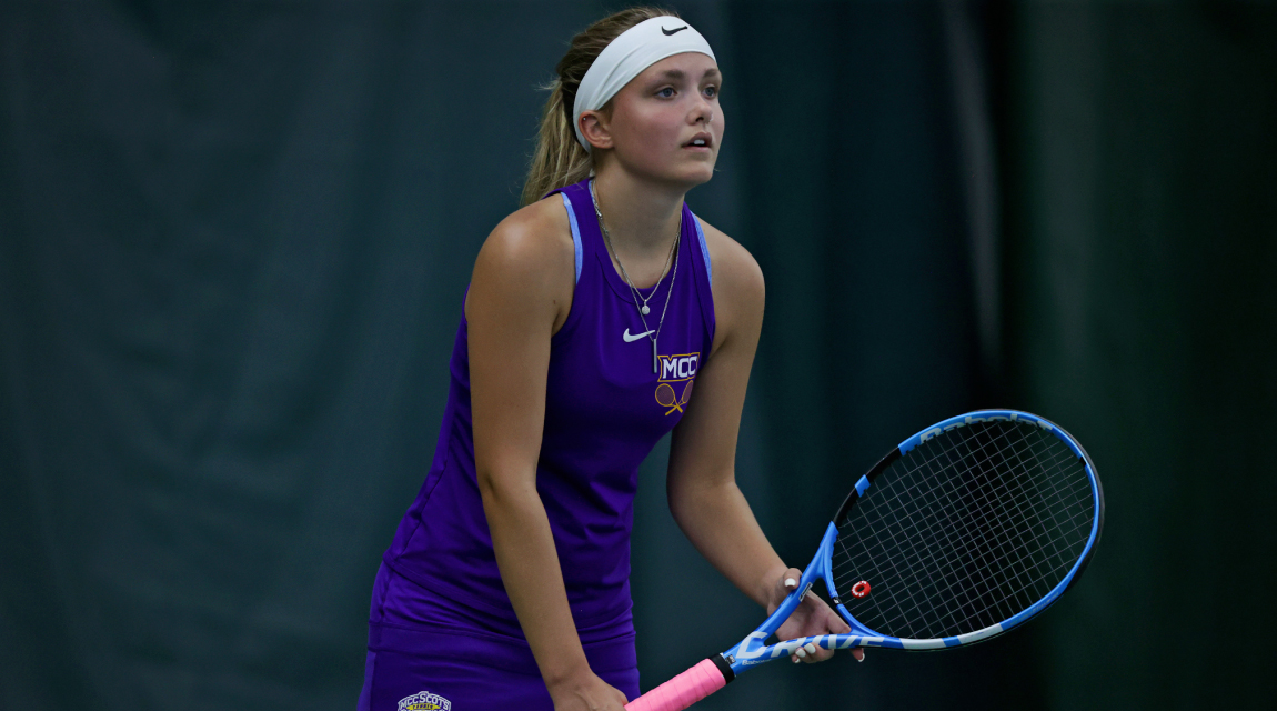 A Scots women's tennis player crouches ready to receive a serve. 